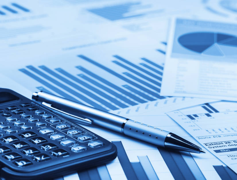 A calculator and pen resting on printouts of charts and graphs