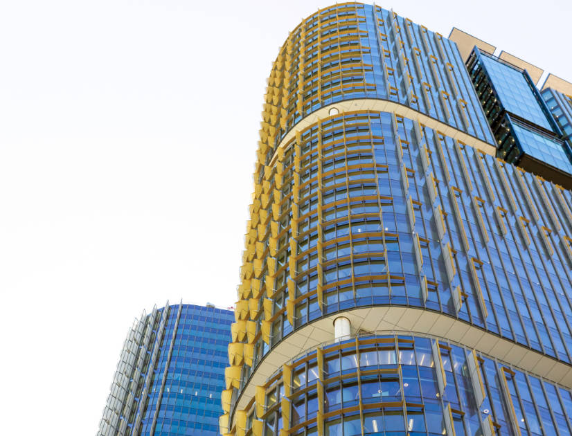 The round, glass and steel face of an urban building against the bright sky