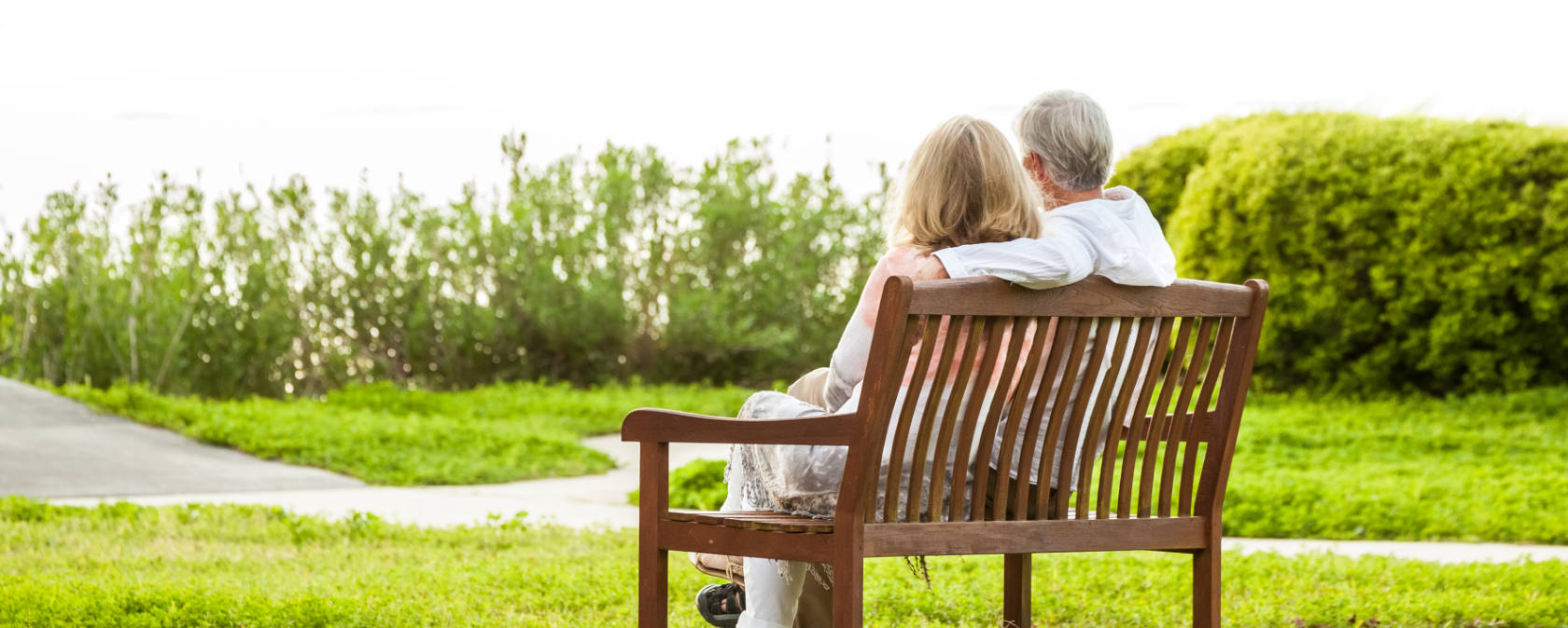 A silver-haired couple sitting on a park bench