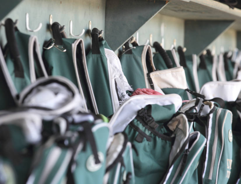 Green schoolbags hung up in a row