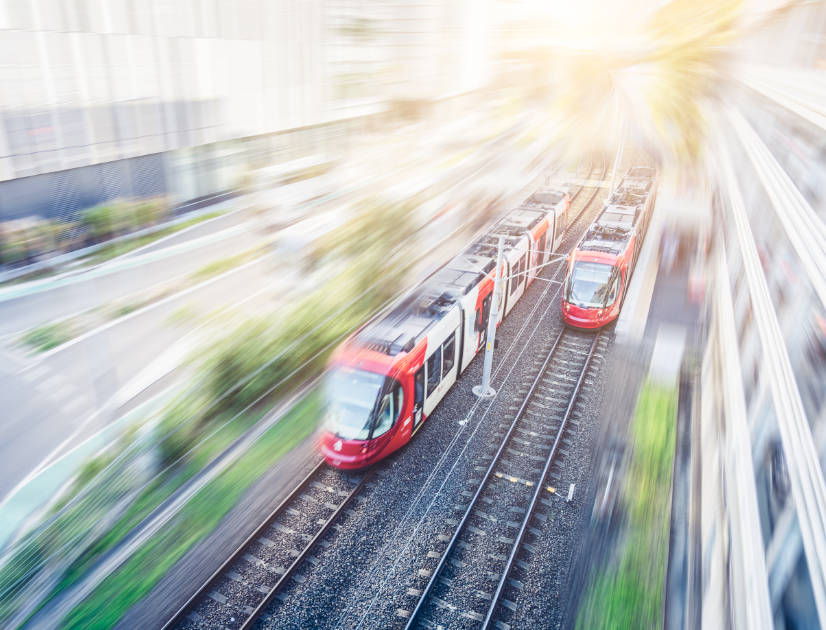 Two trams speed down a pair of light rail tracks